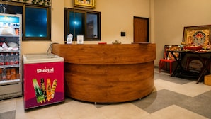 Een receptie met een houten balie, een koelkast met drankjes en een religieus altaar.