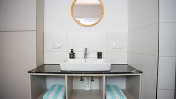 A bathroom with a white sink, a mirror, and two towel racks with towels.