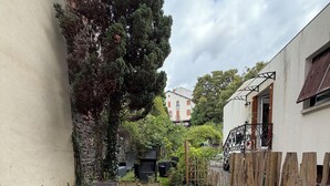 A patio with a table and chairs, surrounded by potted plants and a stone wall. - Charmant T2 avec Terrasse et Jardin - Le Gamay (Châtel-Guyon)