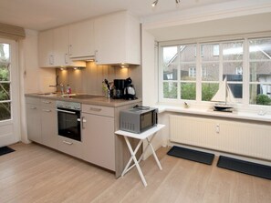 Une cuisine moderne équipée d’un four encastré, d’un four à micro-ondes et d’une petite table.