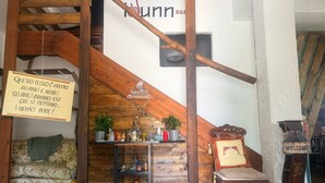 A cozy interior with a wooden staircase, a sofa, a shelf with various items, and a 'Welcome' sign. - Room 'Dea' with Shared Pool, Wi-Fi and Air Conditioning (Santa Marinella)