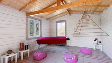 Una habitación con techo de madera, una mesa roja y dos pufs morados.