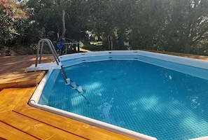 Una piscina rettangolare con una scaletta su un lato, circondata da un pontile in legno.