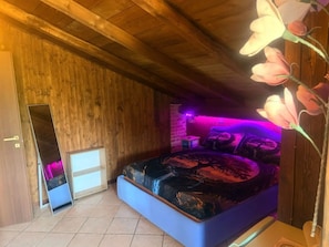 Una camera da letto con un letto, uno specchio e un soffitto in legno.
