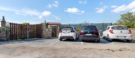 Three cars parked in a lot with a stone gate and a sign that reads 'Land of Freedom'.