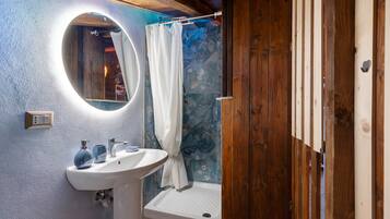 A bathroom with a white sink, a mirror, a shower curtain, and a wooden door.