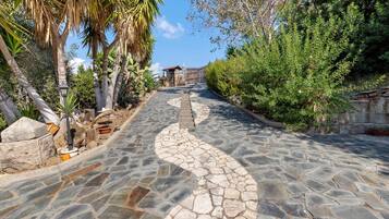 A stone pathway leading to a building with a wooden fence and a gate.
