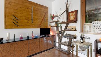A kitchen with a wooden wall, a TV, and a decorative tree shelf.