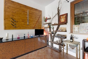 A kitchen with a wooden wall, a TV, and a decorative tree shelf.