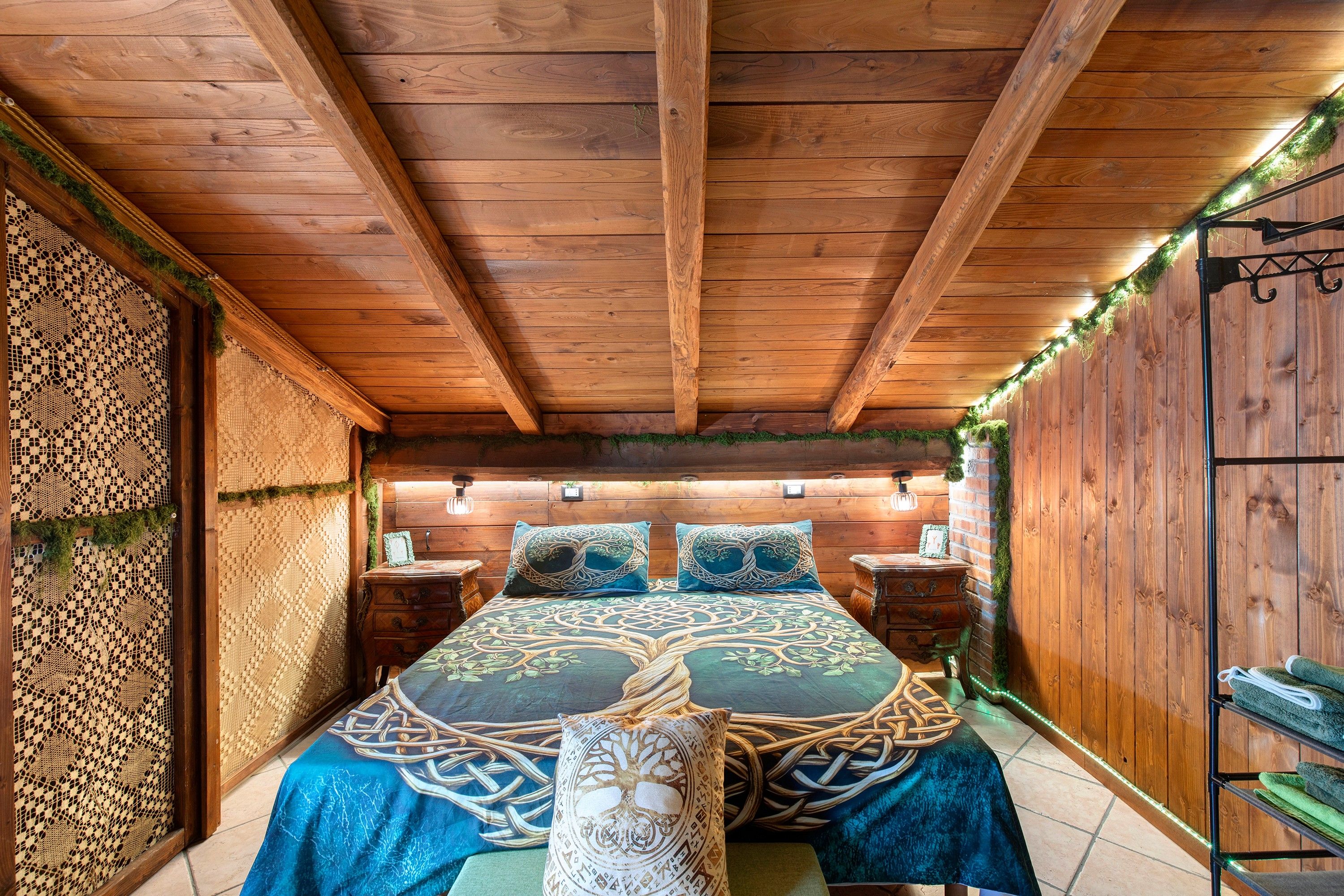 A wooden room with a bed, nightstands, and a decorative wall.