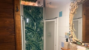 A bathroom with a shower door, a wooden vanity, a mirror, and a tiled wall. - Room 'Terra' with shared pool, Wi-Fi and air conditioning (Santa Marinella)