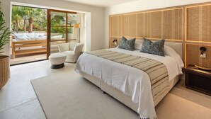 Ein modernes Schlafzimmer mit einem großen Bett, einer Sitzecke und einer Glastür zum Balkon.