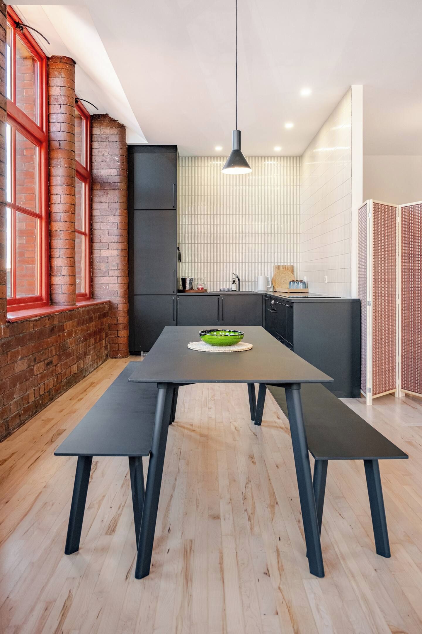 A modern kitchen with a central island, a dining table, and a hanging pendant light.