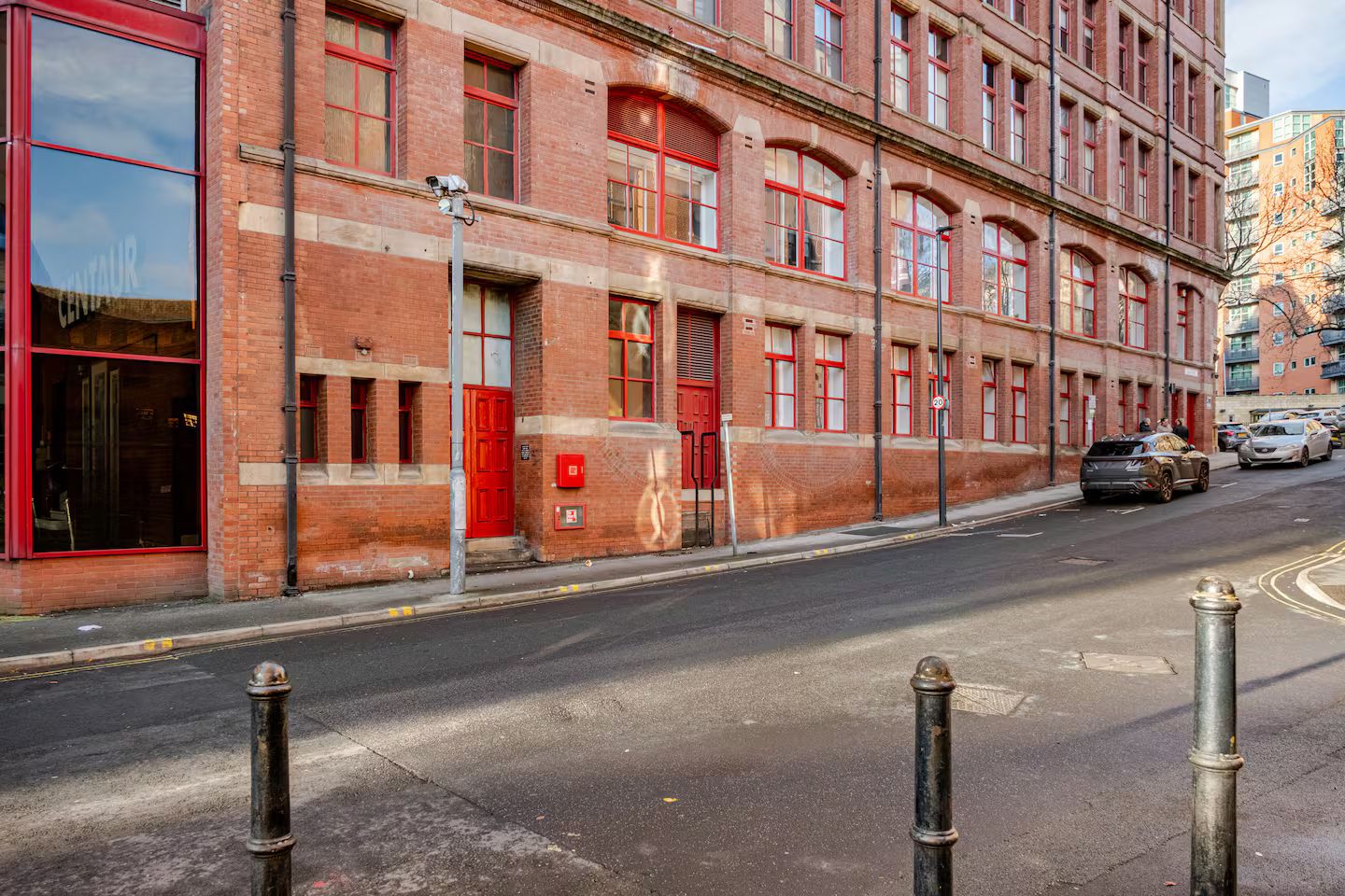 A red brick building with large windows and a red door.