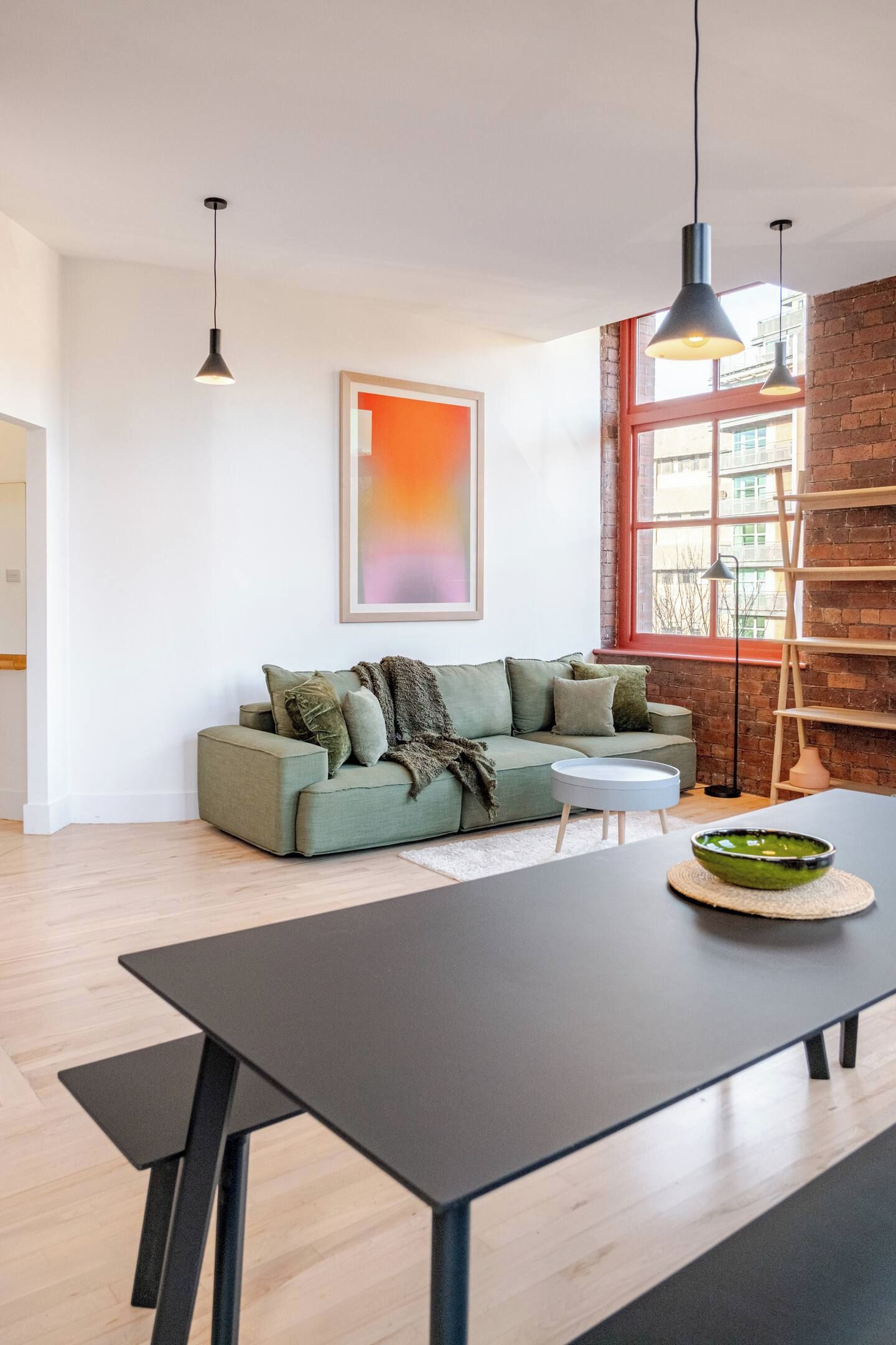 A modern living room with a sofa, a coffee table, and a painting on the wall.