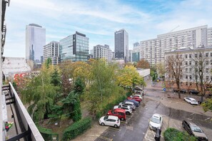 Un parking où sont garées plusieurs voitures, entouré d’arbres et de bâtiments.