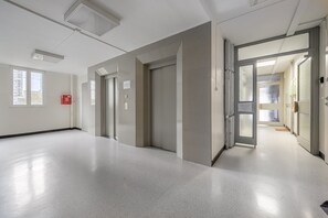 A corridor with doors, a fire alarm, and a view of a building outside. - Lumina comfy apart center of Warsaw  (Warszawa)