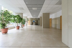 Un hall d’entrée spacieux, doté d’un sol carrelé, de plantes en pot et d’un plafond orné d’un motif en réseau.