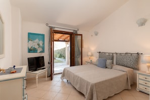 Quarto com cama, mesas de cabeceira, televisão e vista para o exterior.