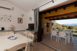 A dining area with a table and chairs, a television, and a view of the outdoors. - Villetta Rosella by Wonderful Italy (Golfo Aranci)