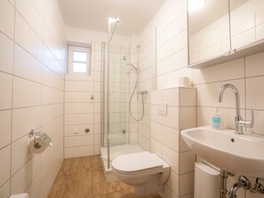 A bathroom with a toilet, a sink, and a shower. - 6 in the Pole Poppenspaler House (St. Peter-Ording)