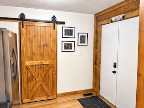 A room with a wooden barn-style door, a white closet, and a refrigerator.