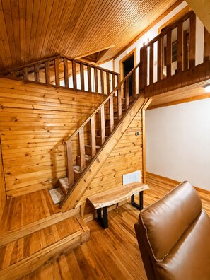 A wooden staircase with a bench at the bottom, leading to an upper level.