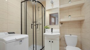 Ein modernes Badezimmer mit einer gläsernen Dusche, einem weißen Waschbecken und einer Toilette.