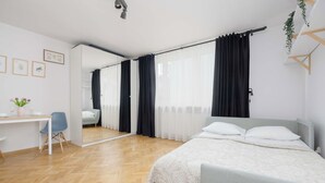 Ein modernes Schlafzimmer mit einem Bett, einem Schreibtisch, einem Stuhl und einem Spiegel.