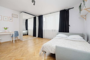 Un dormitorio moderno con cama, escritorio, silla y espejo.