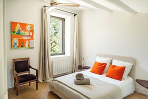 Une chambre d’hôtel avec un lit, une chaise, une fenêtre et un tableau au mur.