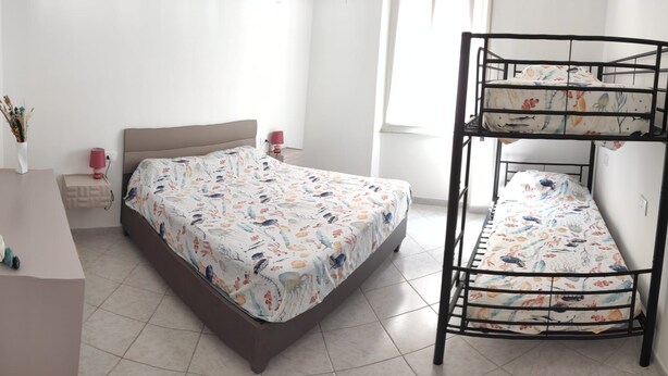 Une chambre avec un lit superposé, une table de chevet, une lampe et un miroir fixé au mur.