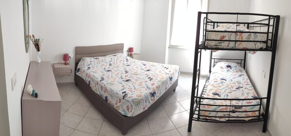 Une chambre avec un lit superposé, une table de chevet, une lampe et un miroir fixé au mur.