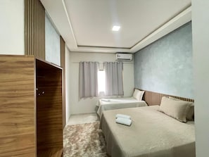 A hotel room with two beds, a wardrobe, an air conditioning unit, and a window with curtains. - HOTEL PÉ DE SERRA  (Piranhas)