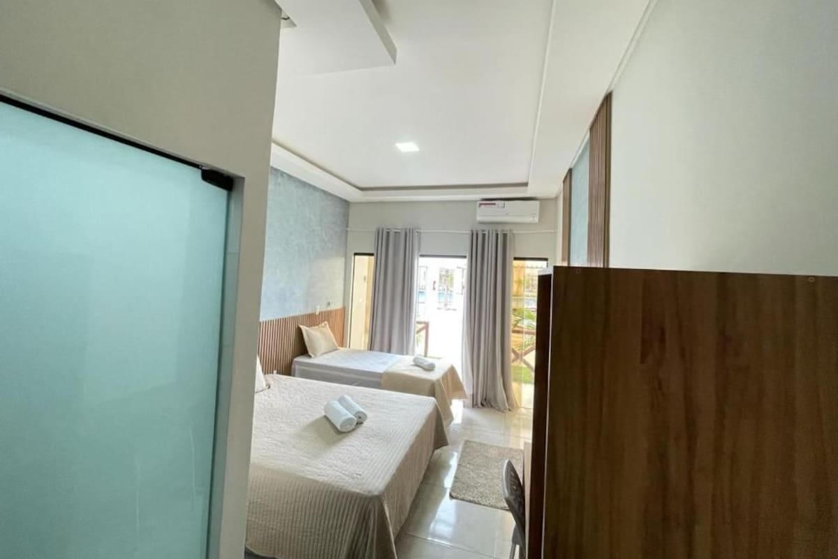 A hotel room with two beds, a desk, and a view of the outdoors.