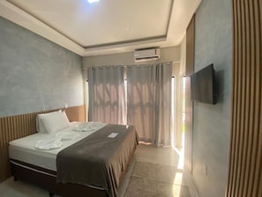 A hotel room with a bed, a flat-screen TV mounted on the wall, and a window with curtains. - HOTEL PÉ DE SERRA  (Piranhas)
