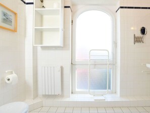 A bathroom with a white radiator, a towel rack, and a shower area with a glass door. - 11 in the House at Blanker-hans-weg 5 (St. Peter-Ording)