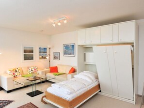 A compact living space with a bed, a sofa, a glass coffee table, and a wardrobe. - 11 in the House at Blanker-hans-weg 5 (St. Peter-Ording)