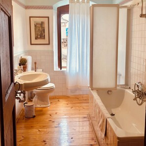 A bathroom with a wooden floor, a bathtub, a sink, and a toilet. - Vrbo Property (Cison di Valmarino)