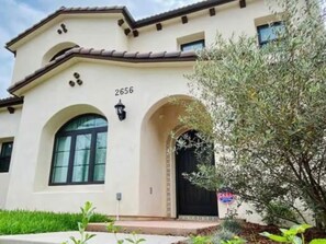 A two-story house with a beige facade, a black door, and a number '2656' on the wall.