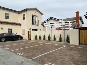 A parking area with marked spaces, a black car parked, and a building with a beige facade and a red roof.