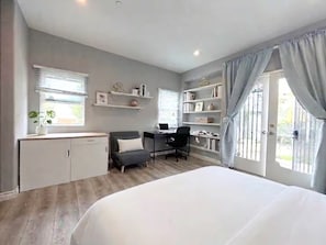 Ein Schlafzimmer mit einem Bett, einem Schreibtisch, einem Stuhl, einem Kleiderschrank und Regalen mit Büchern und Dekoration.
