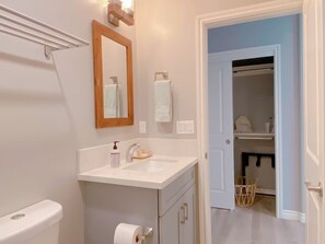 A bathroom with a toilet, sink, mirror, and a towel rack.