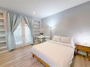 Une chambre à coucher avec un lit, une table de chevet, une lampe et une fenêtre avec des rideaux.