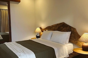 Ein Hotelzimmer mit einem Bett, zwei Nachttischlampen, einem hölzernen Kopfteil und einem Spiegel.