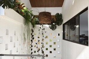 Ein modernes Interieur mit weißer Wand, einer hängenden gewebten Leuchte und einem Fenster mit Blick.