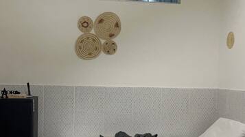 A hotel room with a bed, a small table, a wall-mounted air conditioner, and a window with a view.