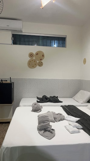 A hotel room with a bed, a small table, a wall-mounted air conditioner, and a window with a view. - Pousada Aconchego (Alter do Chão)