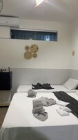 Habitación de hotel con cama, una mesita, aire acondicionado instalado en la pared y ventana con vistas.