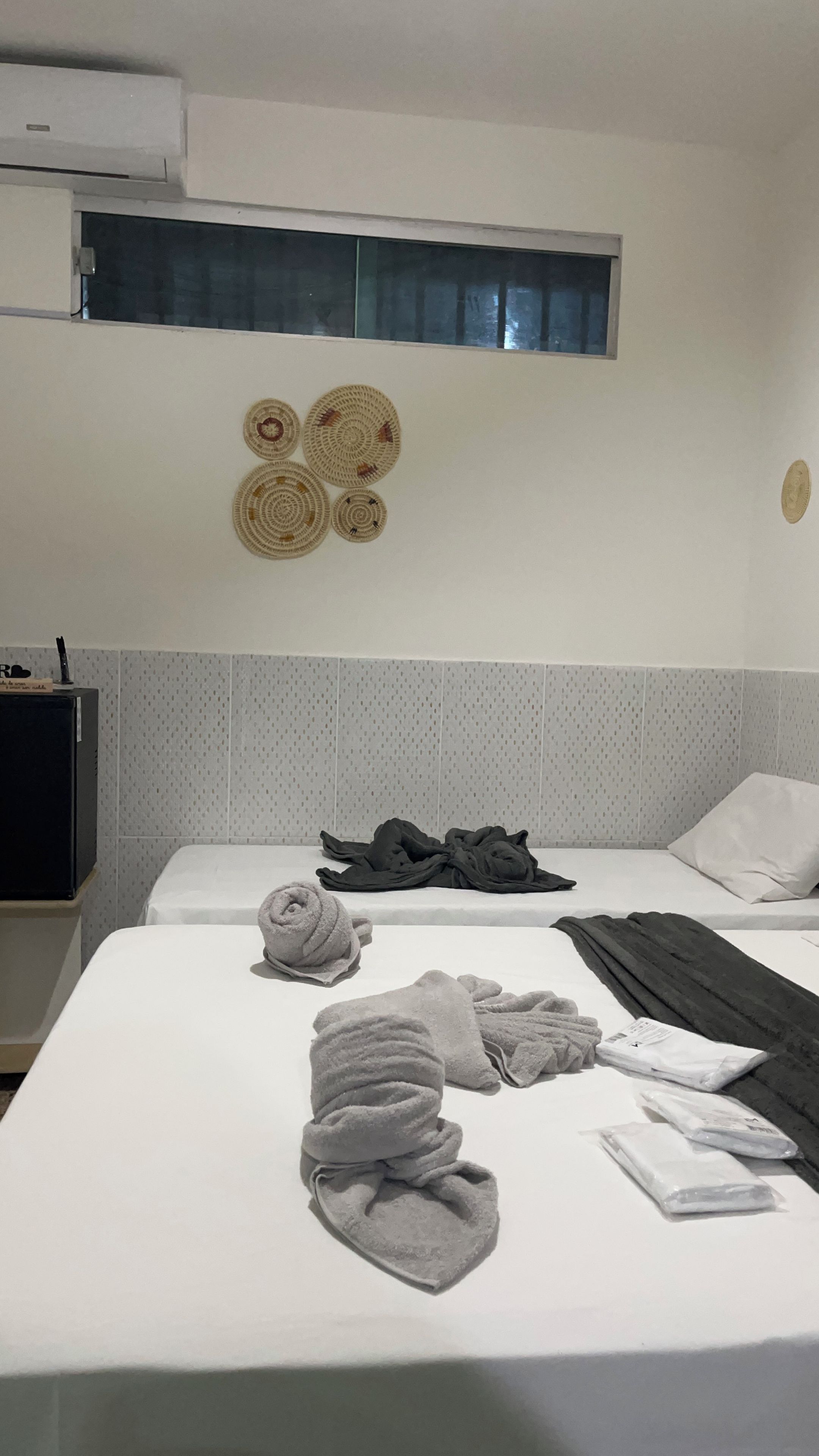 A hotel room with a bed, a flat-screen TV, and a wall-mounted air conditioner.